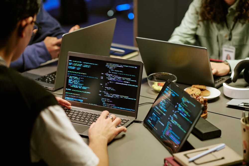 Pessoas trabalhando em equipe com código em notebooks